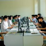 A group of students focused on computer tasks in a classroom setting, fostering teamwork.